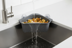 Triangular dark gray sink strainer basket catching curry and food particles while water drains