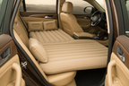 Beige inflatable car bed with two pillows installed across a car rear seat